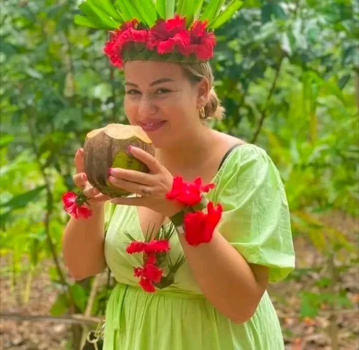 Guest wearing a flower and palm-leaf crown while holding fresh coconut at a Zanzibar Spice Farm