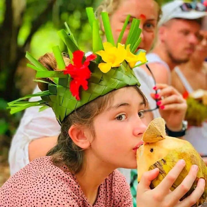 Young guest wearing a woven palm-leaf crown and enjoying fresh coconut at a Zanzibar Spice Farm