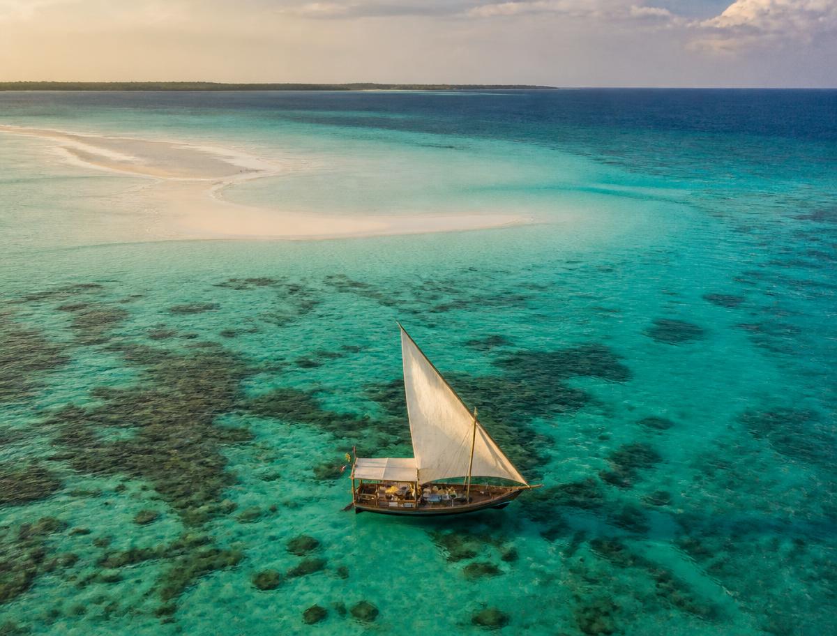 Traditional dhow sailing over the clear water around Mnemba Atoll